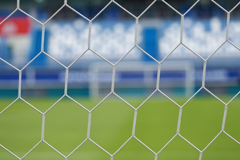Pitch and Blue Stadium Seats Through Goal Net
